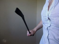Cara Sutra holding a black riding crop, an implement for Femdom punishment and correction tasks