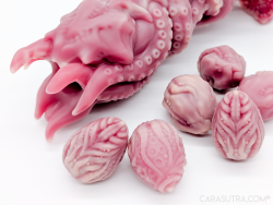 Close up of the tip of the Nothosaur Kohana Ovipositor Dildo, with a selection of KoXeno silicone eggs nearby, on a white background