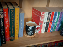 Writing With a Spine A warm wooden bookshelf with books on either side and a tea cup resting in the empty space where a book would normally sit