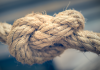Close-up of a thick rope tied in a firm knot, showing texture and wear