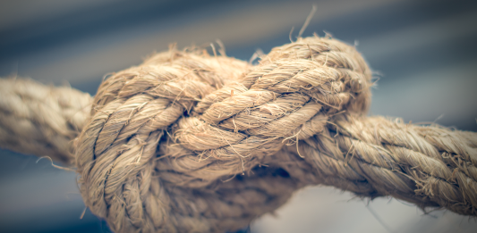 Close-up of a thick rope tied in a firm knot, showing texture and wear