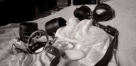 BDSM Aftercare Guide: Emotional Drop, Recovery and Staying Connected After Play Leather cuffs and collar resting on soft bedding after a BDSM scene