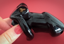 Black chastity cage held in hand representing keyholder control in BDSM chastity dynamics