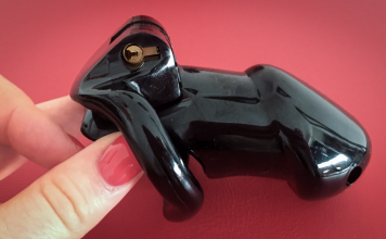 Black chastity cage held in hand representing keyholder control in BDSM chastity dynamics