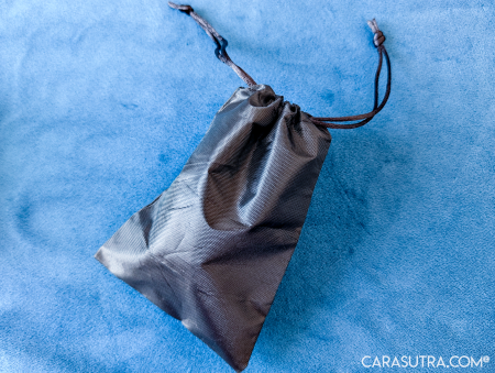Black drawstring storage pouch supplied with the GITM Playbook Cupcake Vibrator, shown closed on blue velvet