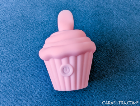 Front view of the pink Cupcake Vibrator showing the raised circular power button with power symbol on the cake case