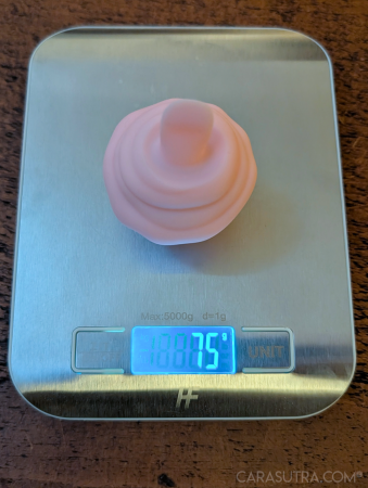 Pink Cupcake Vibrator upside down on a digital kitchen scale showing a weight of 75g, confirming the manufacturer's stated weight