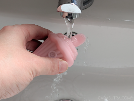 Pink Cupcake Vibrator being carefully rinsed under a running tap, showing the recommended cleaning method given the toy's ambiguous IPX6 to IPX7 waterproof rating