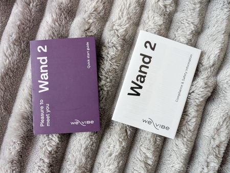 We-Vibe Wand 2 quick start guide and compliance and safety information leaflets side by side on a grey blanket