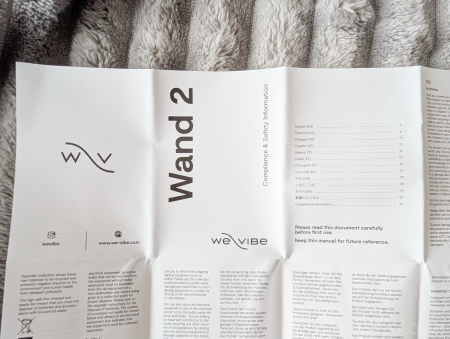 We-Vibe Wand 2 compliance and safety information leaflet unfolded on a grey blanket