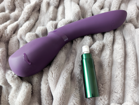 We-Vibe Wand 2 vibrator on a grey blanket next to a shiny green canister of sex lube