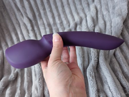 We-Vibe Wand 2 held horizontally in hand from above, showing the head shape and curve of the handle