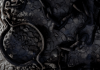 Rusted iron shackle and tangled chains on cold stone floor, cool-toned close-up