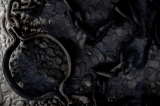 Rusted iron shackle and tangled chains on cold stone floor, cool-toned close-up