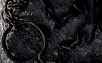 Rusted iron shackle and tangled chains on cold stone floor, cool-toned close-up