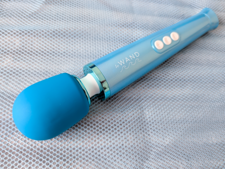Le Wand Dive submersible wand vibrator in Pacific Blue lying on a grey mesh surface, showing full length with silicone head, three white buttons and tapered handle