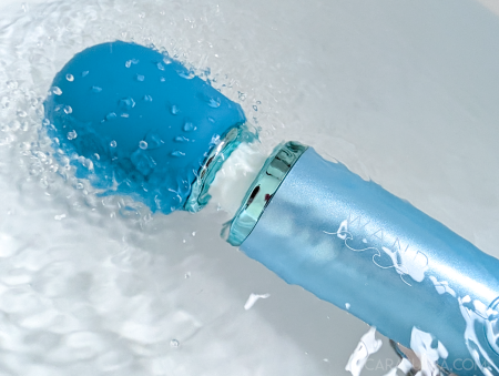 Le Wand Dive vibrator partially submerged in bathwater, silicone head under the surface with water rippling around it