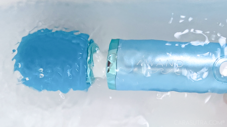 Top three quarters of Le Wand Dive vibrator shown horizontally, head pointing left, with the entirety of the toy's head and body under clear water with a white background