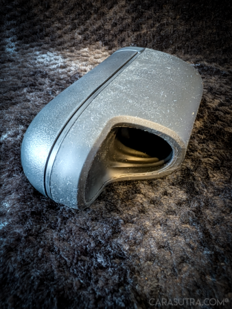 Arcwave Ion 2 black silicone stroker resting on its side on a black blanket, angled to show the sleeve opening and the twist line between the two sections