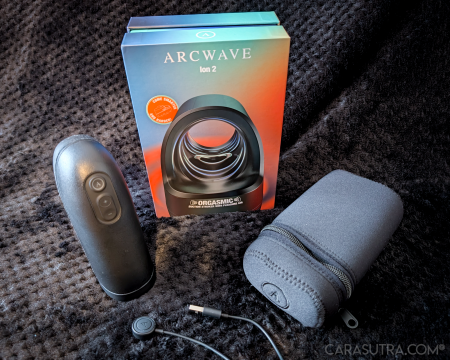 Arcwave Ion 2 retail box standing upright on a black textured blanket, with the black stroker and black storage pouch beside it